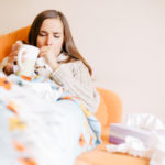 Sick young woman is coughing on the couch